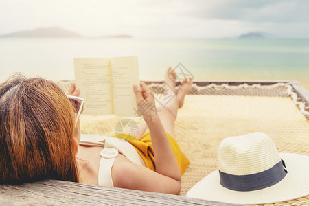 女在节假日暑自由时间阅读关于吊床上海滩的书籍休息室海洋亚洲人图片