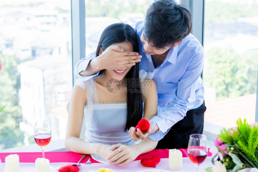 情人节和亚裔年轻快乐的情侣概念以订婚戒指的男人为例午餐后向女求婚在餐馆背景新娘和郎婚礼计划中在新郎和娘结婚计划中珠宝亲热餐厅图片