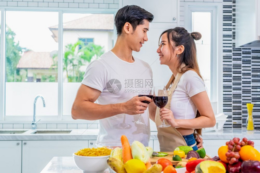 快乐的亚洲年轻已婚夫妇喝着葡萄酒在厨房里互相寻找男朋友和女一起做饭人们的生活方式和浪漫关系概念情人节是情人节的一日健康酒鬼家图片