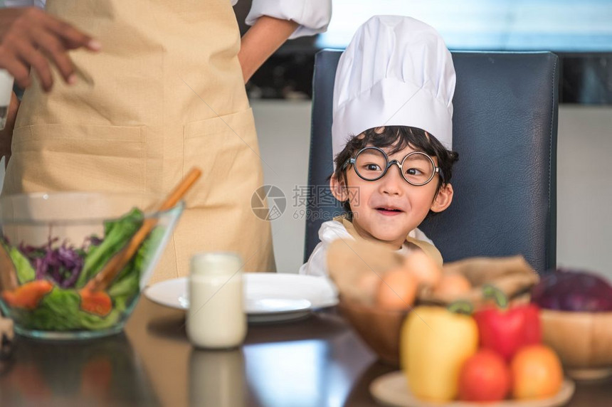 孩子们一顿饭脸穿着大厨帽和围裙的亚洲可爱小男孩与母亲在家中厨房泰国人和生活方式概念工作职业和教育学习概念以及快乐家庭时日主题的关图片