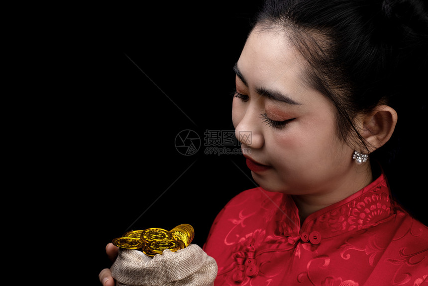下巴新的亚洲年轻穿红礼服的亚洲女传统青森在黑背上袋中拿着金币的黑衣长袍女孩新年概念古董图片
