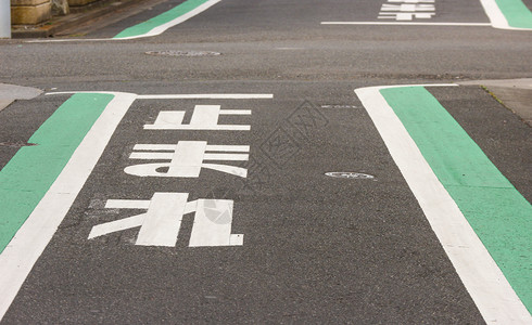 标记路线肮脏的从日本语角度看待在Balck水泥混凝土街道地上的文字符号意思是禁止骑自行车或汽的人寻找安全地方背景