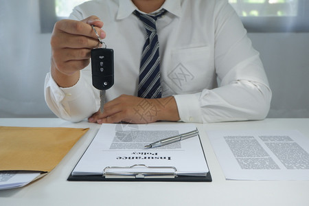 签约推销员银行业在签署文档后给一辆车键的COLseup手图片