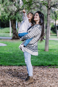 母女士亲在美丽的早晨抱着女儿在公园周围玩耍妈图片