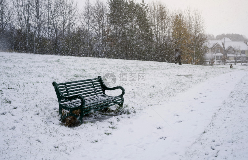 降雪公园的金属板凳在WInter有雪覆盖WInter一个孤单的绿色长椅在公园的共小路冷若冰霜图片