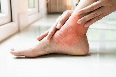 触碰妇女脚踝受伤触摸脚疼痛治疗亚洲背景图片