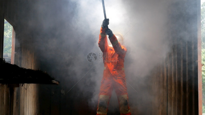 为了消防员用水管化学泡沫喷洒剂发动机与火焰战斗的消防员Fierman戴硬帽身穿防火灭器方面的营救训练制服援工作图片