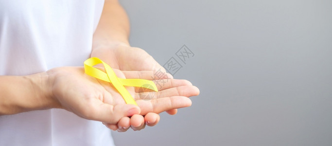 手握黄色丝带预防癌症概念图片