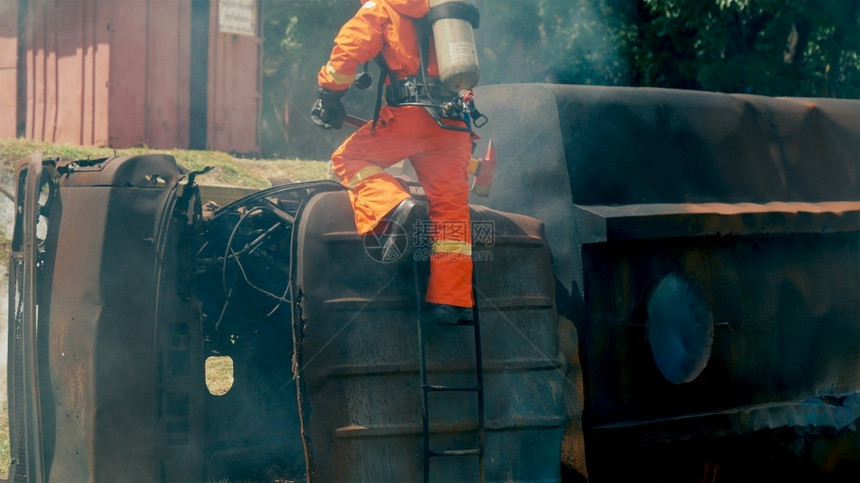 黄色的消防员用水管化学泡沫喷洒剂发动机与火焰战斗的消防员Fierman戴硬帽身穿防火灭器方面的营救训练制服头盔热的图片