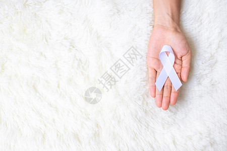 手握白色丝带预防癌症概念图片