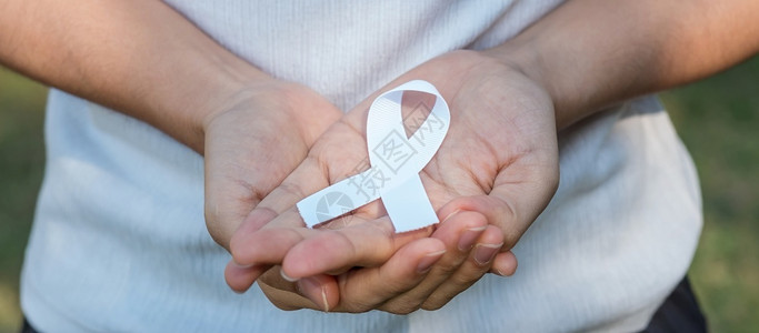 手握白色丝带预防癌症概念图片