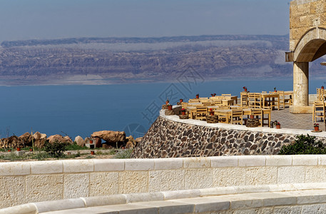 在约旦死海博物馆的露台和以色列山丘在对岸中东面的以色列山上看到盐渍的著名安曼背景图片