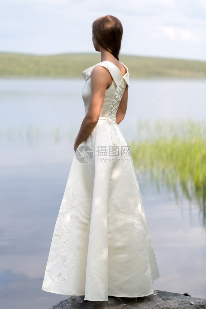 身着白色衣服的女孩站在岩石上湖的背面从看一眼春天脸种图片