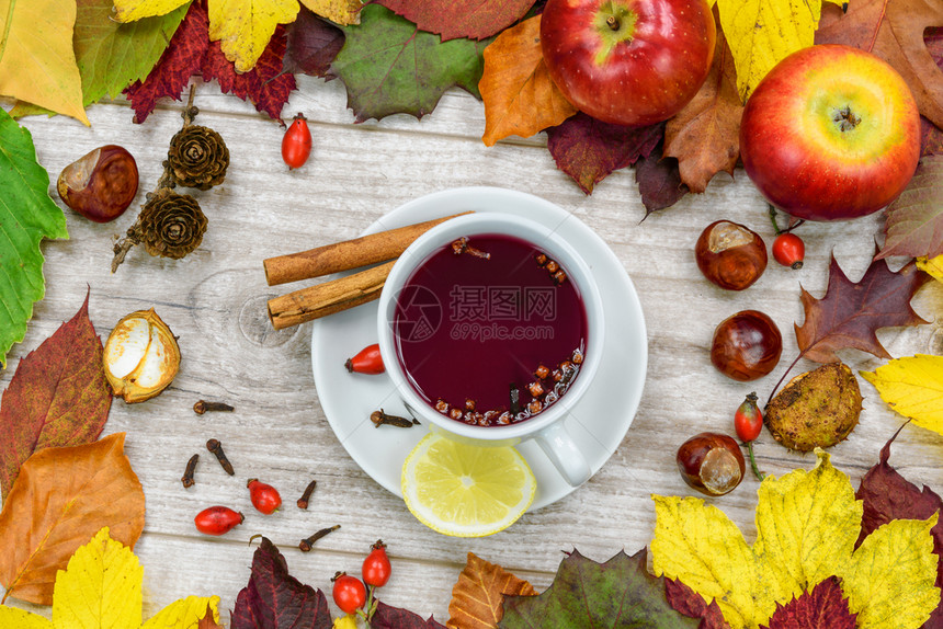 热的高架枫喝杯茶盛满野玫瑰配有香料和柠檬周围是秋天的古典装饰图片