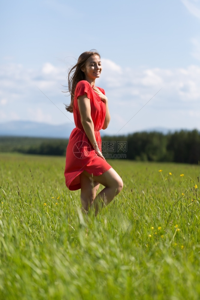 天空松弛愉快一在田里穿红礼服的年轻女孩图片