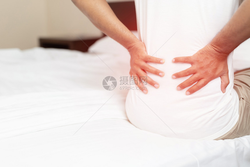 身体睡衣关心一个在床上背痛的男人图片