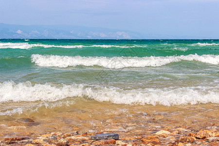 俄罗斯西伯利亚夏季旅游节奥卡孔岛BaikalPebble湖海滩泊纯绿水和蓝天的色空上出现明亮风雨天气和海浪的景象夏天自然力量图片