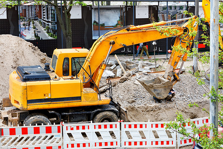 技术的重改造型建筑挖掘机在有围栏的建筑工地上作为城市公用事业挖沟重型道路掘机在建筑工地挖沟背景图片