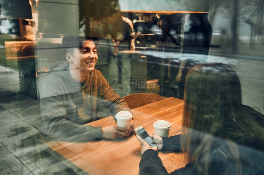 热的上市销售朋友聊天一起喝咖啡坐在厅里年轻男人和女在咖啡厅里放松休息图片