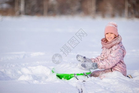 坐在雪地上玩耍的小孩图片