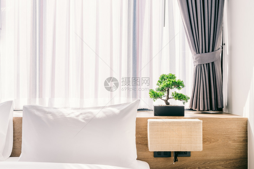 在床上装饰紧贴白色枕头的里面有灯光和绿树在旅馆卧室内的花盆里有绿树家具色明亮的图片