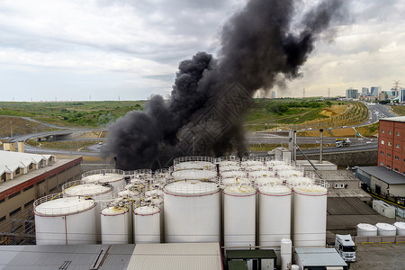 动态工厂屋顶在能源箱上燃烧火焰和黑烟超过厚的背景