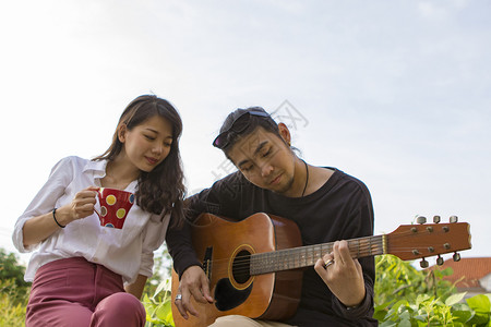 音乐家在公园里弹吉他时放松的情侣和女人在公园里弹吉他男生玩图片