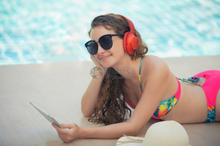 泳衣美女游泳池边听音乐闲暇图片