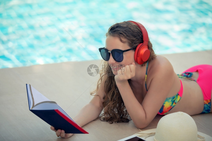 泳衣美女游泳池边看书听音乐图片