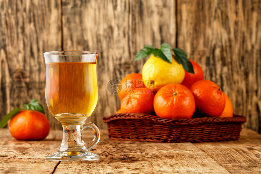 绿色杯子里的柑橘茶凉爽季节的温暖健康饮酒在模糊的旧木桌上堆在圆筒篮子的普通话和柠檬水果的背景将Citrus空间茶复制在一个玻璃杯图片