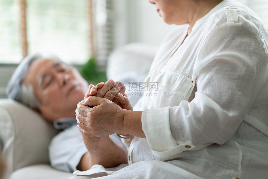 尽管寒冷的亚洲老年妇女在男子发高烧时手握大男子的年老夫妇一起安慰症状疾病和不适图片