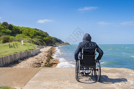 患病的成人独自坐在轮椅上看海的残疾青年男子独身残疾人图片