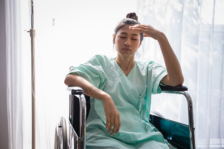 流动身体坐在轮椅上的亚洲女病人在医院头痛房间图片