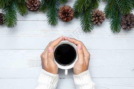 装饰风格冬天抓住手握黑咖啡杯和圣诞节装饰新年快乐和圣诞节日的女子图片
