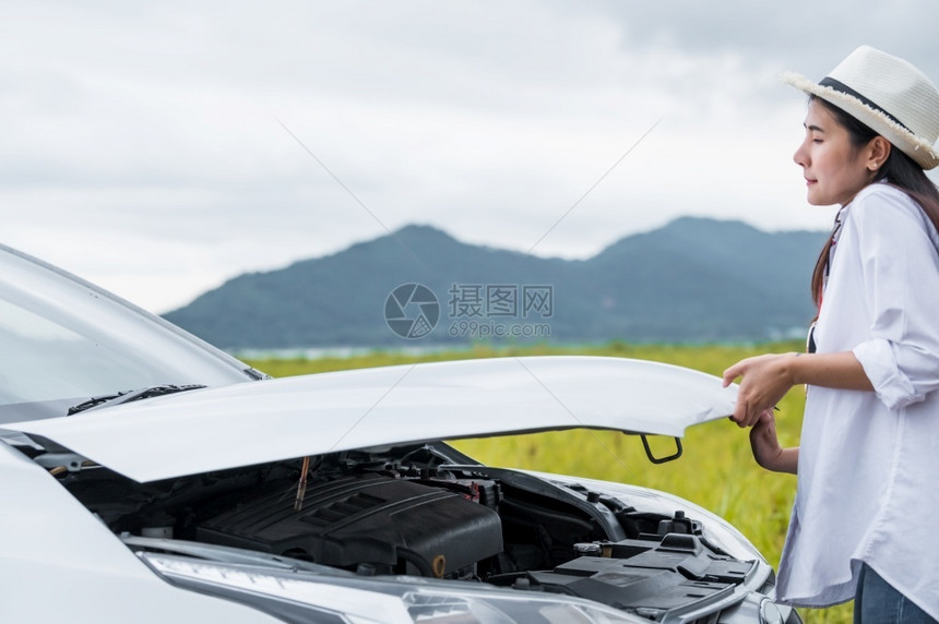 在前往目的地汽车维修和运输概念中人们旅行和风景主题女在开车前往目的地期间独自驾驶汽车保养与交通时为修理破损车辆而打开汽引擎罩经过图片