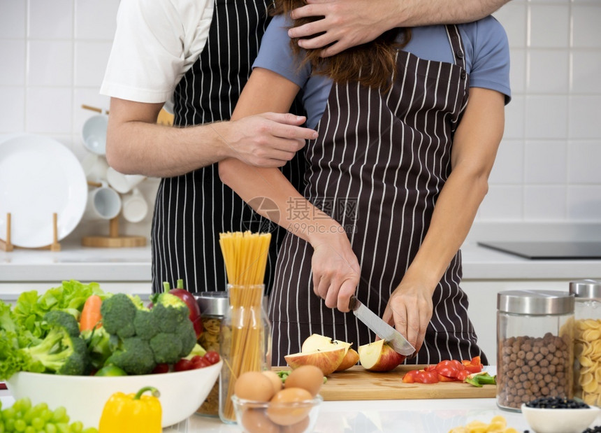 妻子女在切菜板上苹果子男拥抱和站在一对情侣的后面健康食物和家庭烹饪共同概念卫生食品与家庭烹饪杯子图片