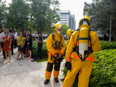 黄西装消防员的后座焦点和面氧气箱的座消防员是教职工他们要逃离高楼大消防车工人男演习背景图片