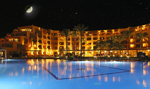 水池畔透明月亮在度假村酒店和游泳池的夜晚和上酒店在度假晚上酒店的灯光在晚上泳池水中反射背景图片
