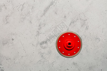 圆形分割素材为了圆圈用钻石切割红色圆盘用一块直径125毫米的薄片和法兰花在灰色混凝土背景下精确切割材料时使用一条直径为125毫米的薄片以灰色背景