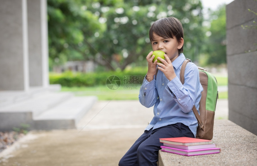 户外拿着苹果准备上学的小男孩图片