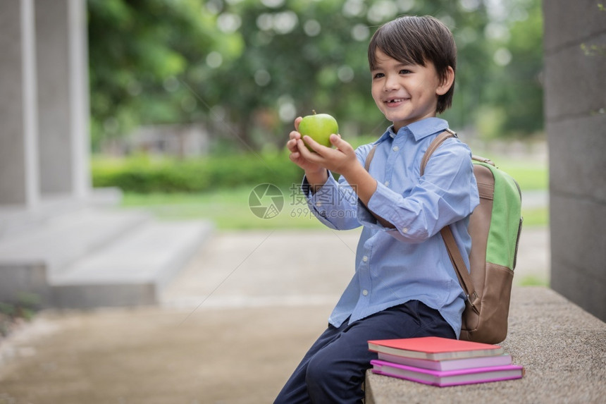 户外拿着苹果准备上学的小男孩图片