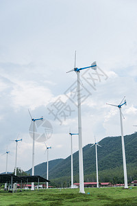 风力涡轮机以近山的绿草地在天空背景下发电机常绿活力图片