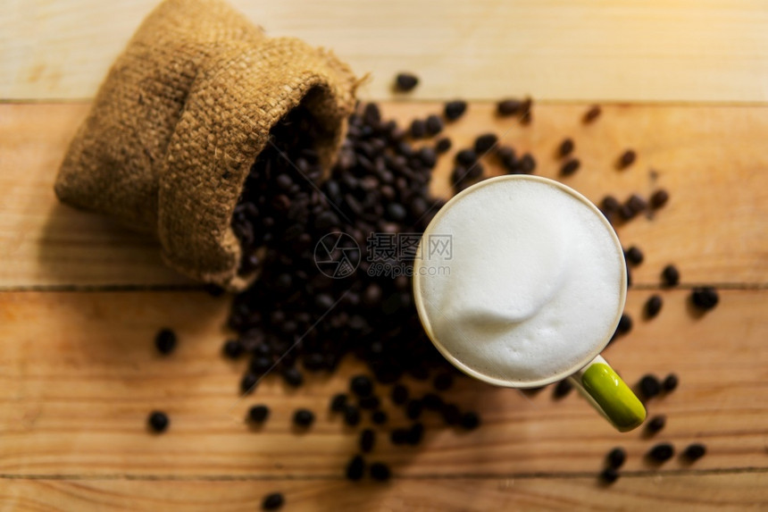 马克杯优质的白色卡布奇诺咖啡和豆在木材纹理背景早晨或咖啡时间餐图片