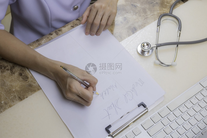 亚洲女医生或护士的高角度视是用听诊器和部分计算机键盘在医院办公室的桌子上写处方并配有听诊器和电脑键盘的一部分亚洲人科学手图片