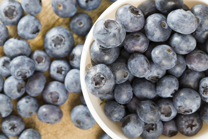 在圆白碗桌边的蓝莓夏季天在木制桌上和盘子散布的成熟而美味果子照片在一张桌子上闭着蓝莓素食主义者早午餐健康图片