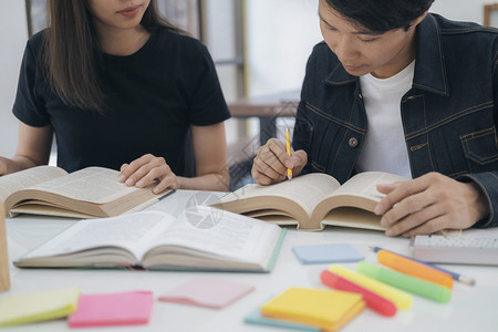 在书桌上一起对着书籍讨论的学生图片