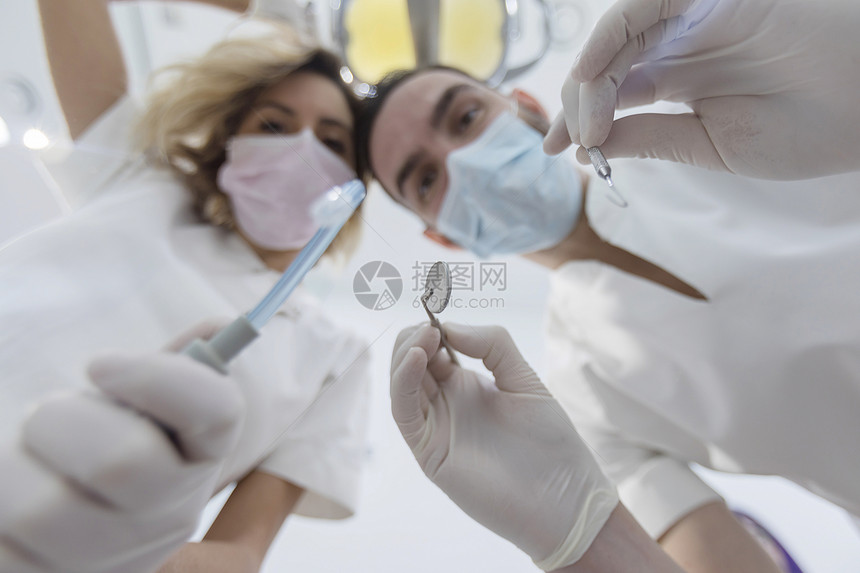 戴着口罩给病人做手术的牙医图片