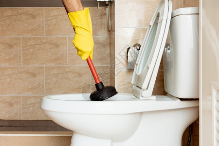戴黄色橡胶手套的人正在使用一个装置来修补堵塞的厕所碗保护专业的洗手间图片