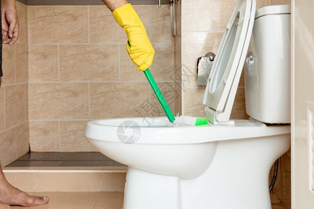 陶瓷制品肮脏的黄色橡胶手套中的人正在用塑料刷洗厕所碗用塑料刷洗白色的图片