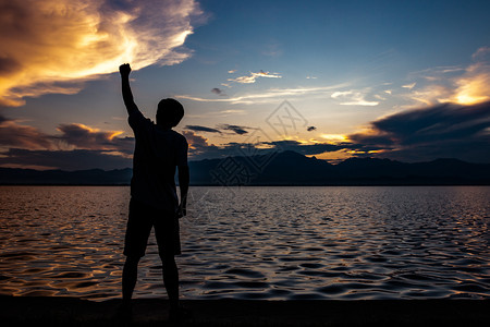 在湖边日落的天空背景下站在湖边欢乐的心情中举起手来乐队汞提高图片